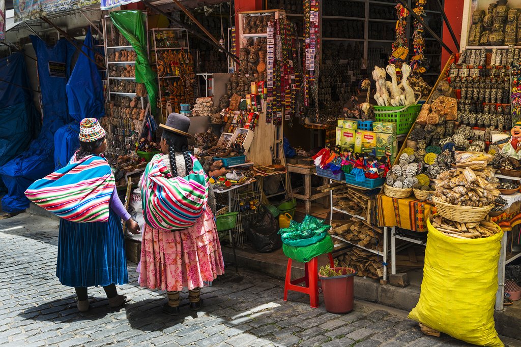 wo local woman wearing traditional clothing in front of a store in a street of the city of La Paz in Bolivia