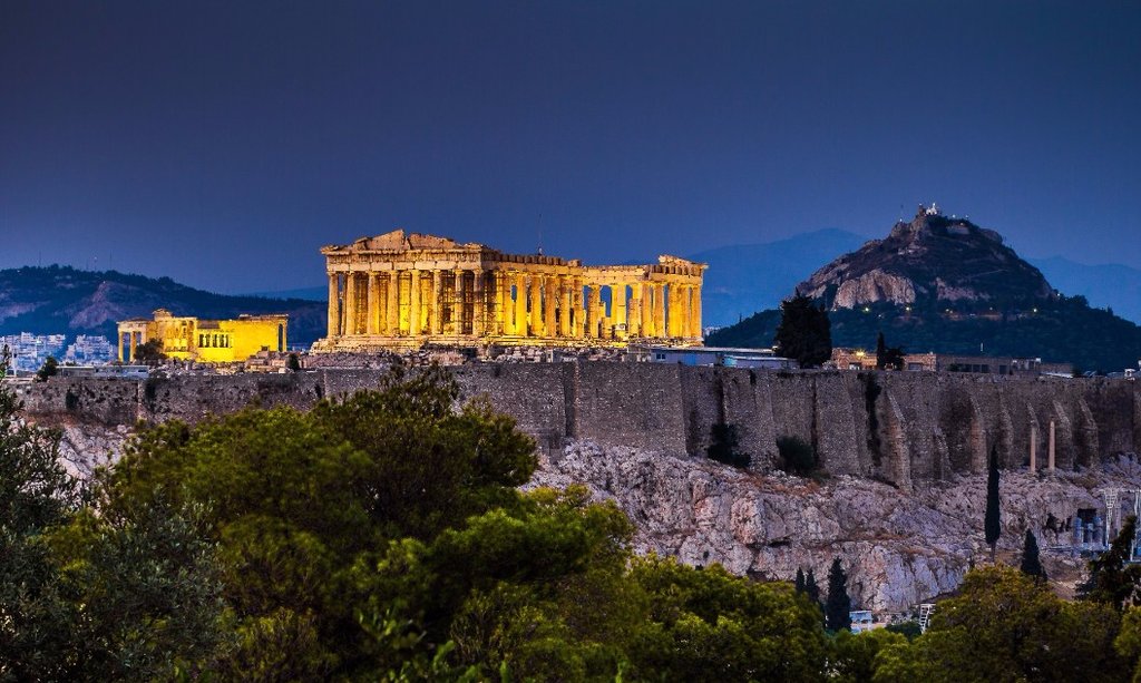 The Acropolis, lit up at night, makes a stunning contrast to the dark sky behind it