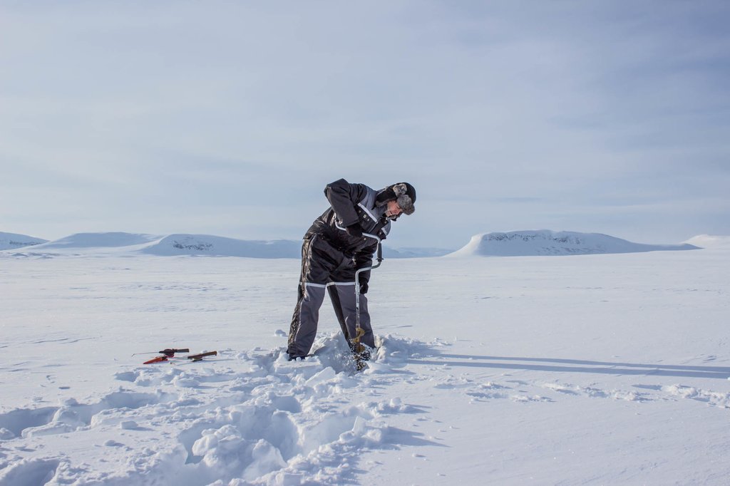An ice fisherman drilling into the lake