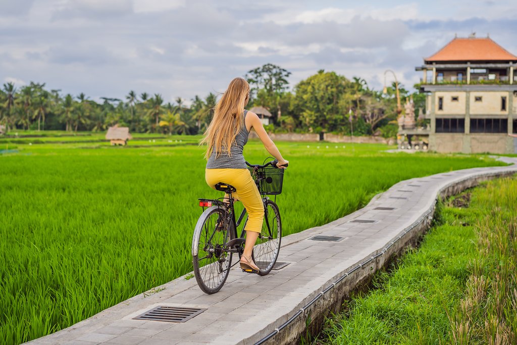 A woman cycling through a rice terrace in Ubud