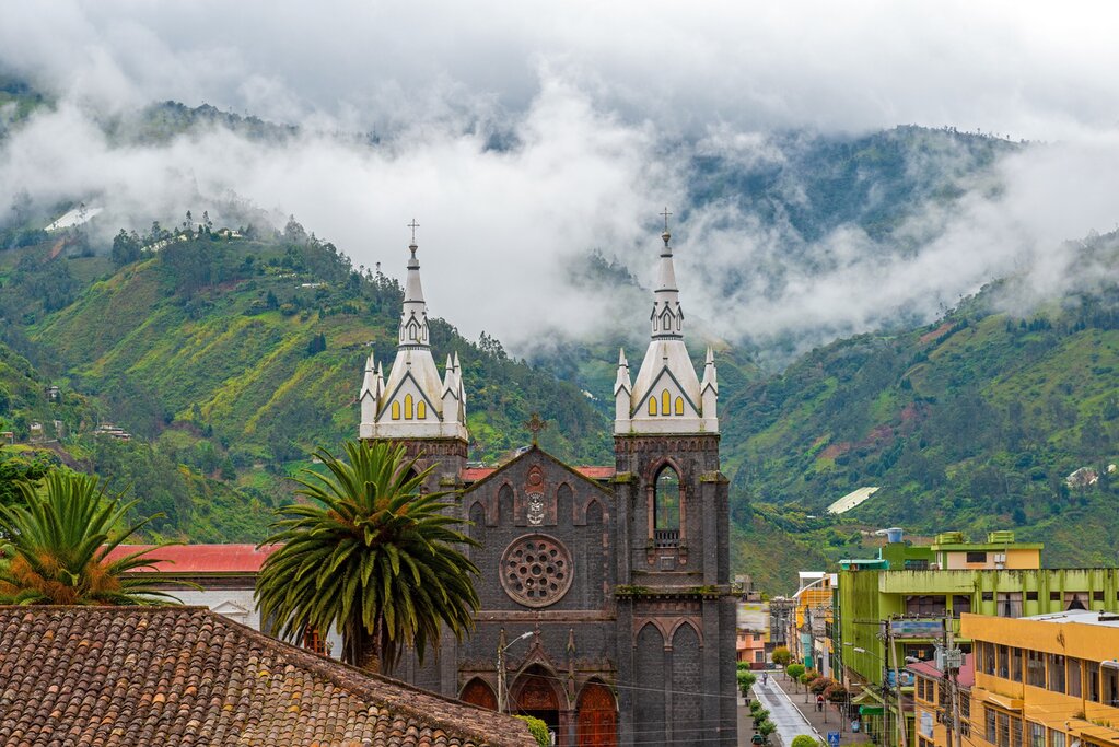 Aerial cityscape of Banos de Agua Santa located in the cloud forest with the bell towers of the Holy Water Virgin Church, Ecuado