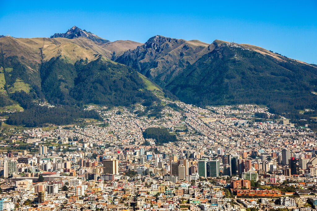Panoramic aerial view of Quito, Ecuador, with mountains in the background.