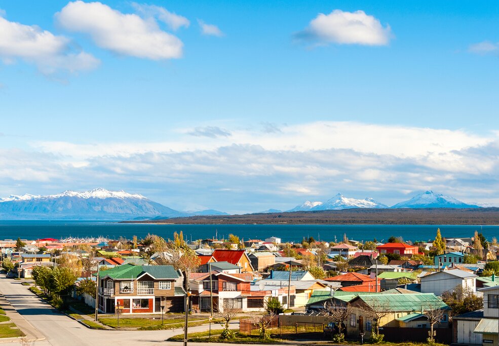 View of houses with colorful roofs on the shores of Señoret Channel with mountains in the distance