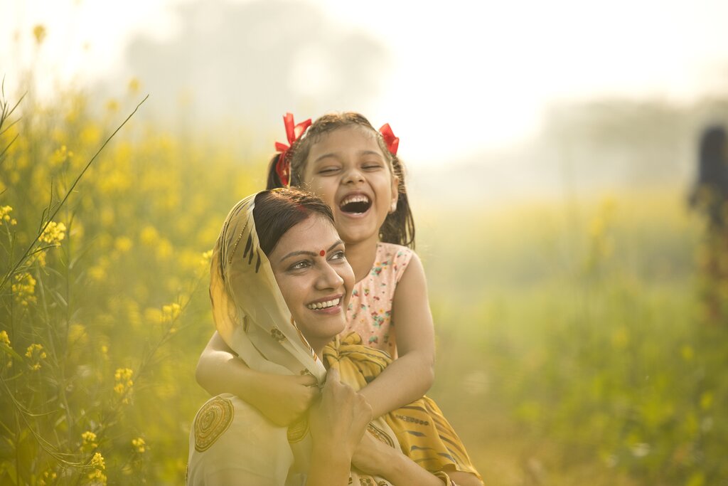 A mother and daughter smiling in an agricultural field in India