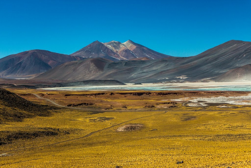Panoramic view of Andean peaks and a mineral-rich lagoon in the Atacama region