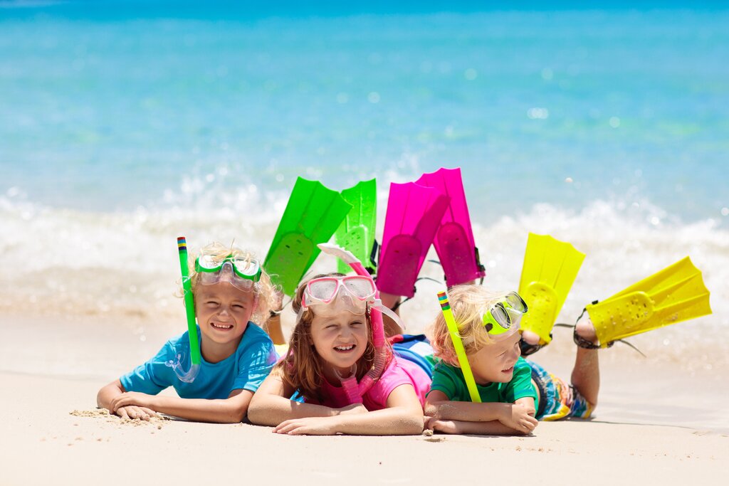 Three children in snorkeling gear on the beach