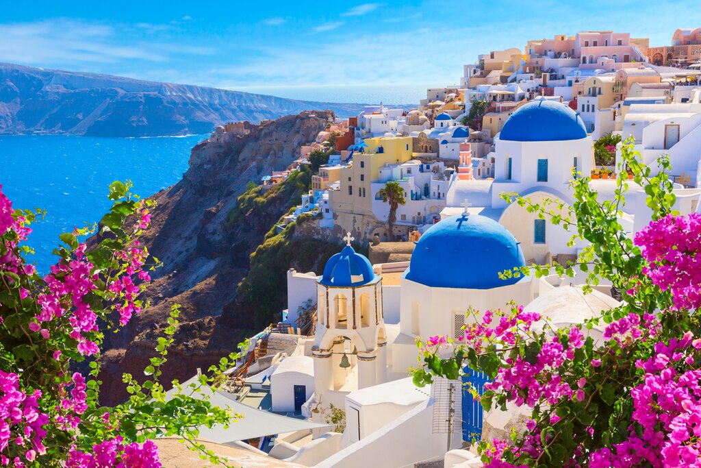 Look out at the glittering sea and colorful buildings in Oia