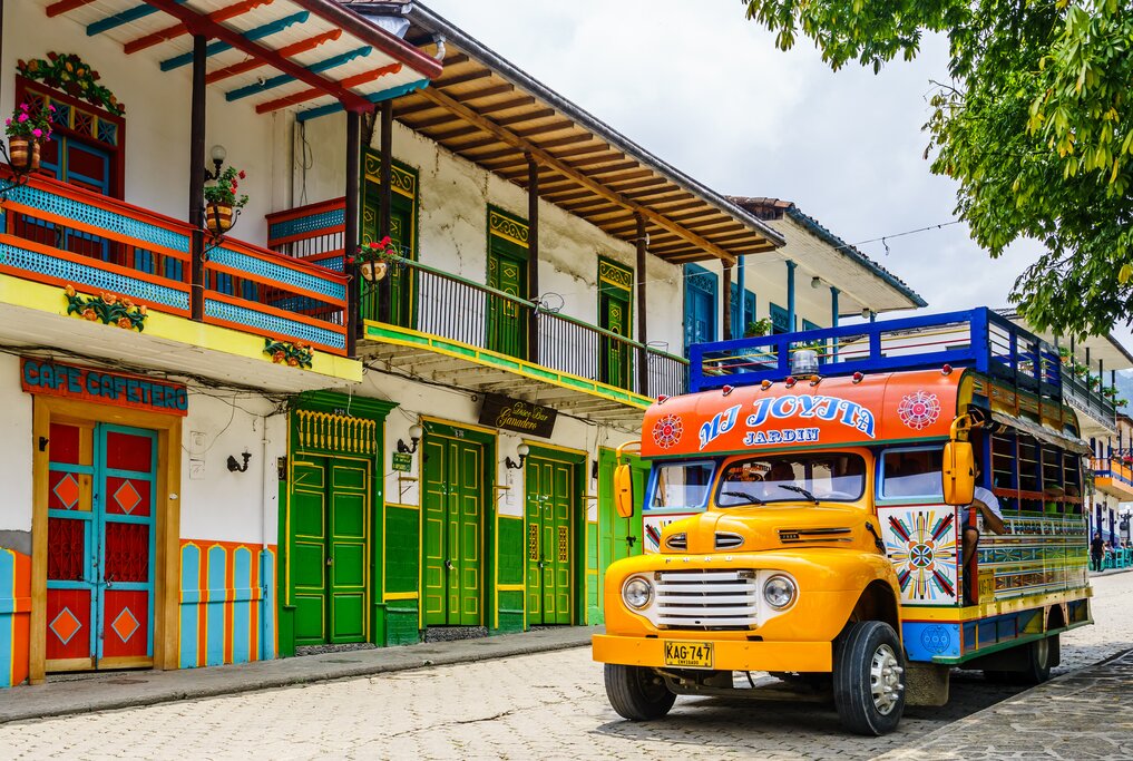 A colorful big bus in front of bright houses