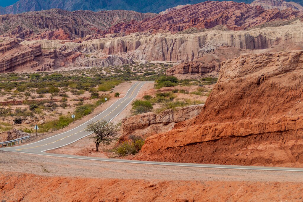 View of a road winding through orange and red canyons in Quebrada de Cafayate