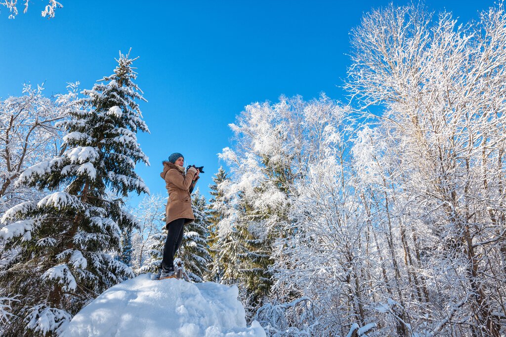 Woman in snowy forest taking a photo