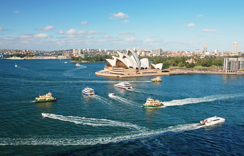 The Sydney Opera House in the harbor with ferries sailing by