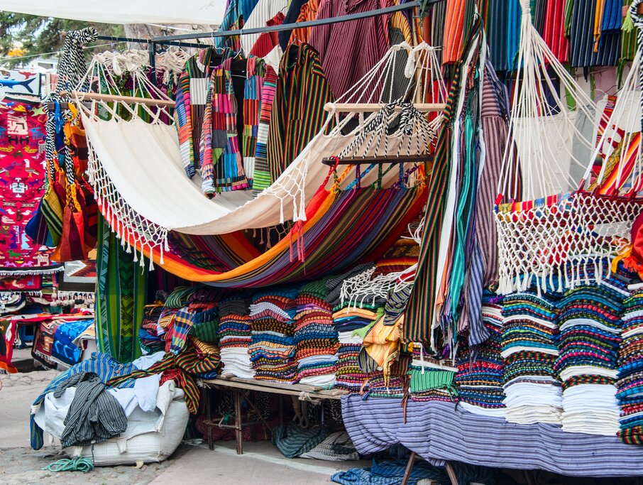 A market stand full of colorful textiles on shelves with hanging hammocks on display