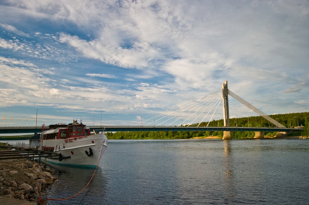 View of Lumberjack's Candle Bridge in Rovaniemi, Finland. A boat is docked near the shore on the left