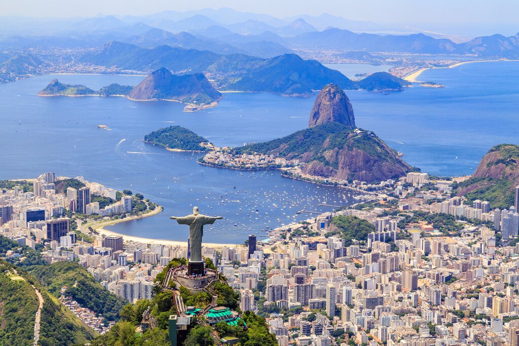 Aerial view of Rio de Janeiro with Christ the Redeemer in the foreground, the city in the middle, and Sugarloaf Mountain and the waters of Guanabara Bay in the background