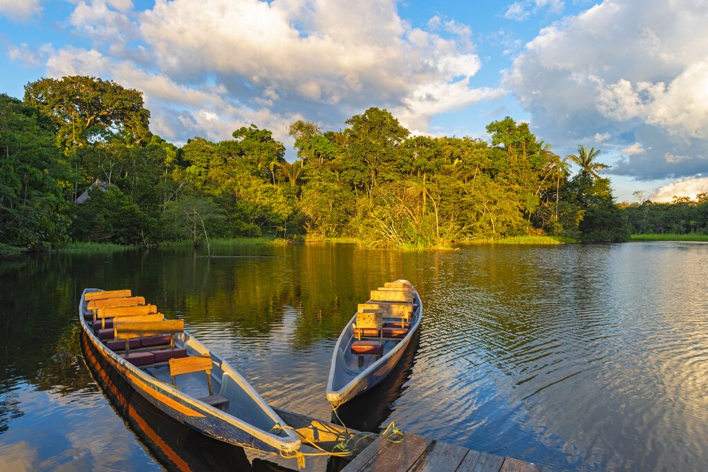 Two traditional wooden canoes at sunset in the Amazon River Basin with the tropical rainforest in the background inside the Yasuní National Park, Ecuador, South America