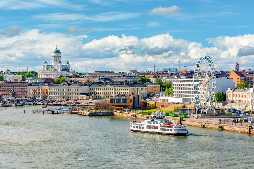 View of Helsinki from the water with Helsinki Cathedral, a boat in the harbor, and a ferris wheel in frame
