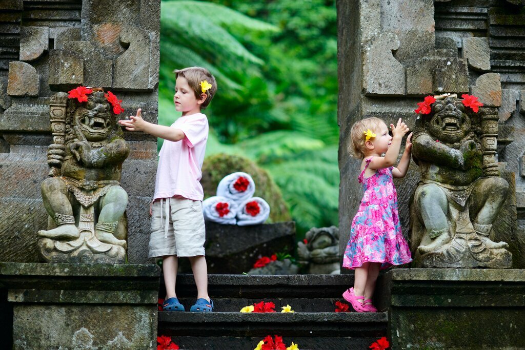 Kids placing flowers on temple statues in Bali