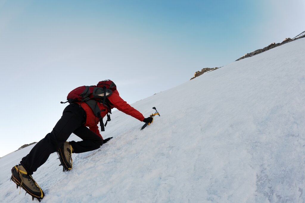 A man using an axe to climb an icy mountain