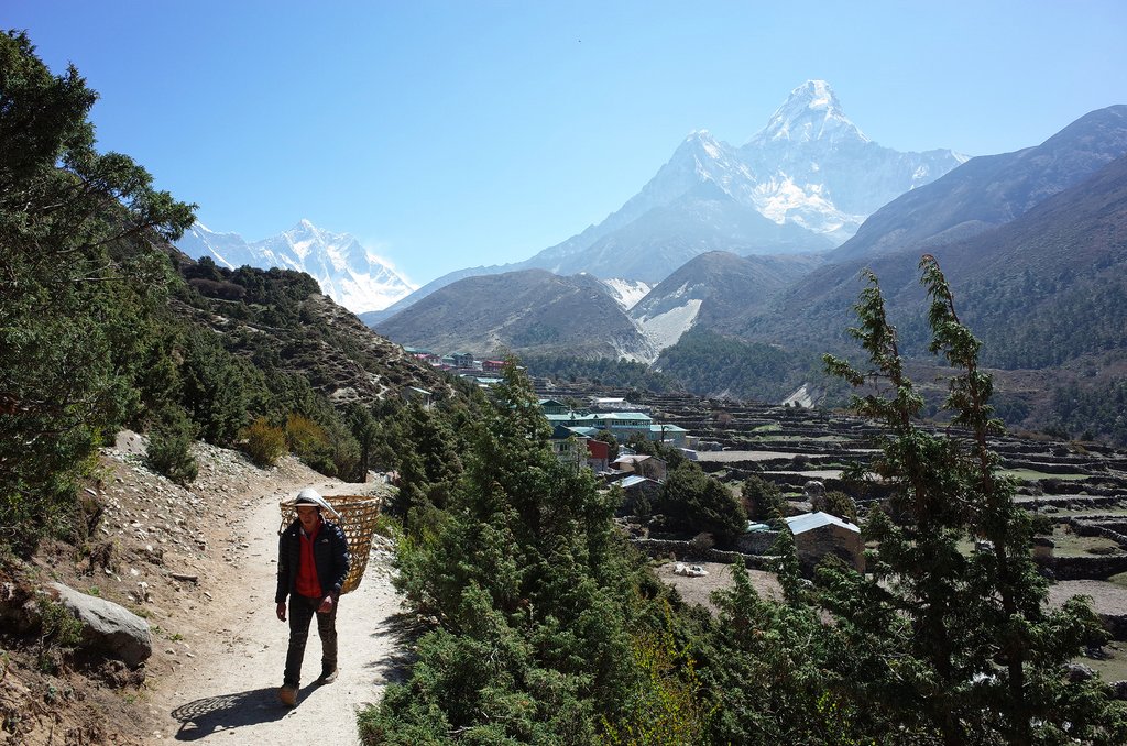 A porter carries a basket on the trail from Pangboche