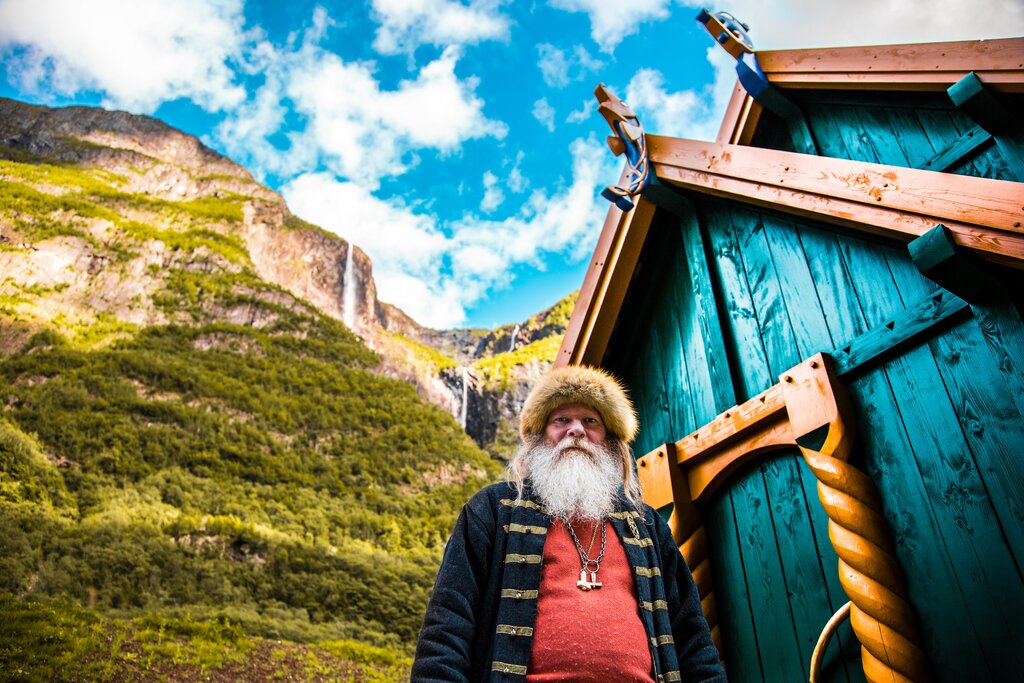 A Viking Village in Gudvangen with the village Chief standing beside his house. [Photo by redcharlie on Unsplash.]