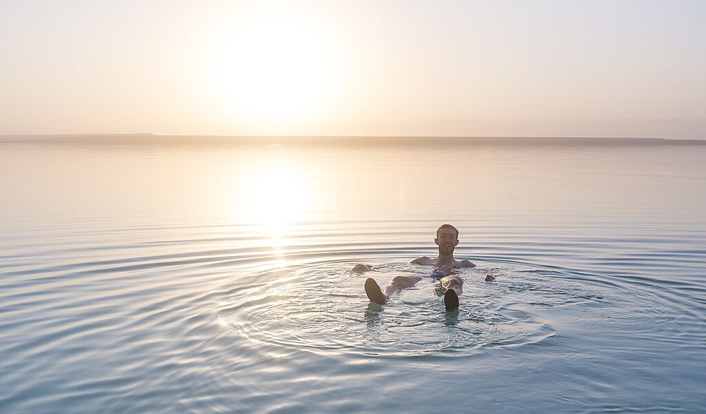 Tourist Sits On The Shore Of The Dead Sea. Jordan Landscape