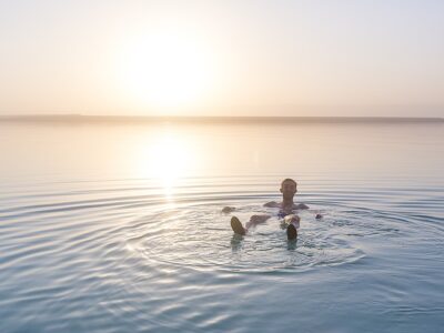 Tourist Sits On The Shore Of The Dead Sea. Jordan Landscape