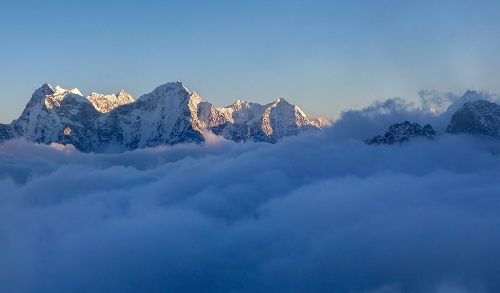 Picturesque Mountain Valley Filled With Curly Clouds At Sunset.
