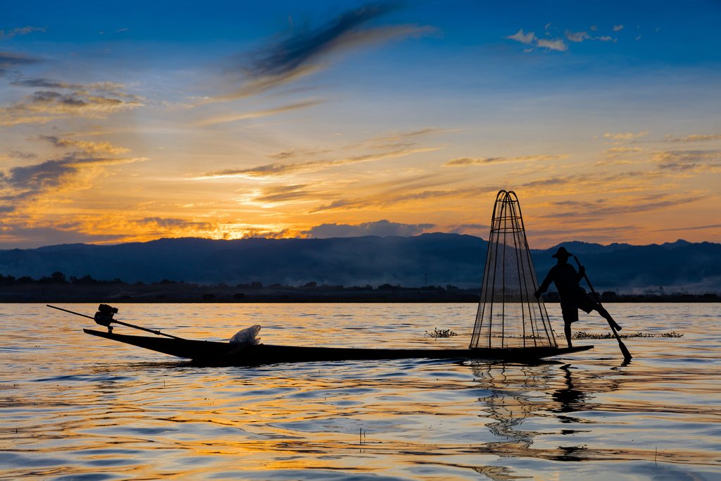 Fisherman demonstrating traditional fishing techniques at sunset