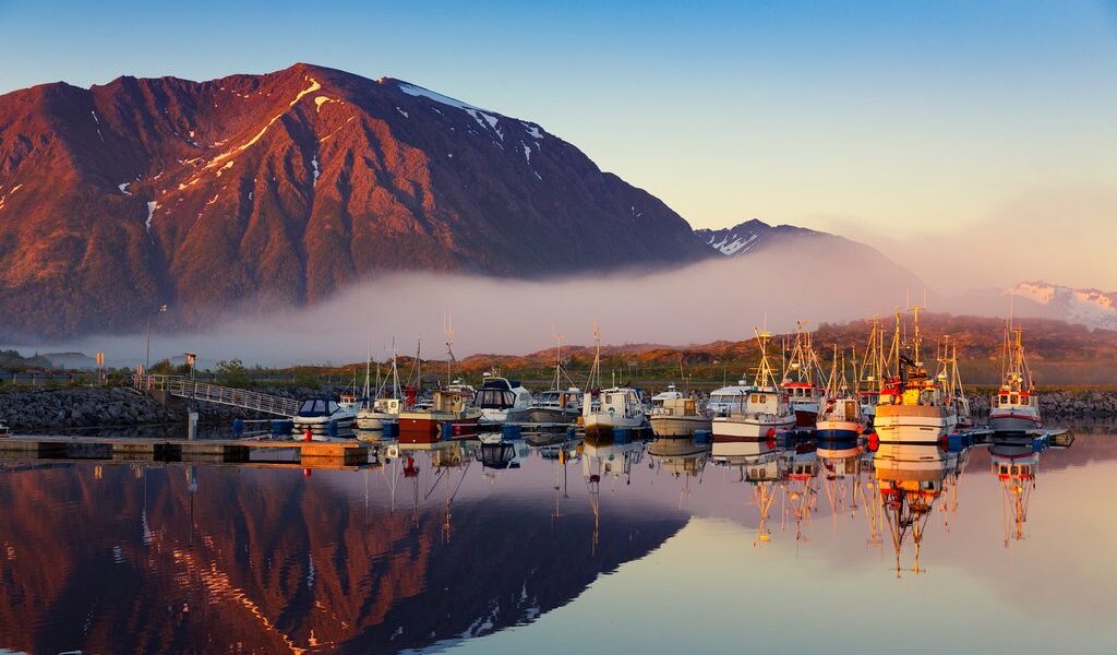 Fishing boats in harbor at midnight sun and fog in Northern Norw
