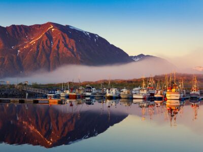 Fishing boats in harbor at midnight sun and fog in Northern Norw