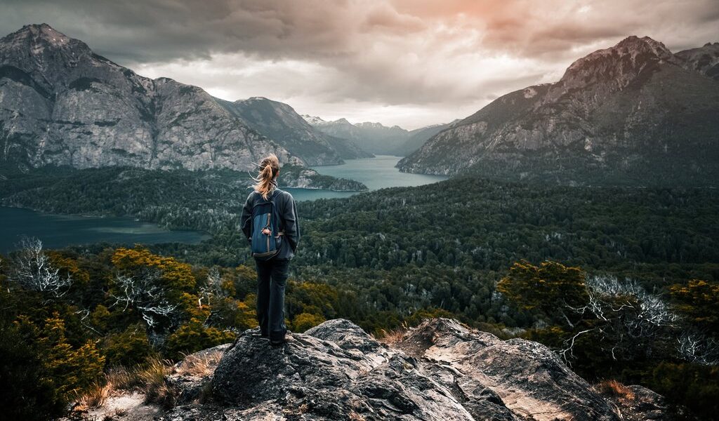 Woman hiker stands and enjoys valley view from viewpoint. Hiker