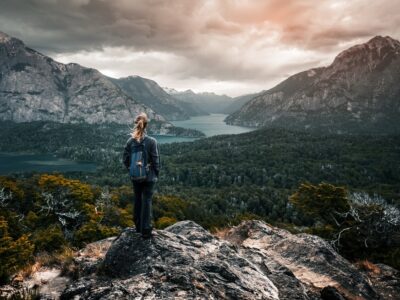 Woman hiker stands and enjoys valley view from viewpoint. Hiker