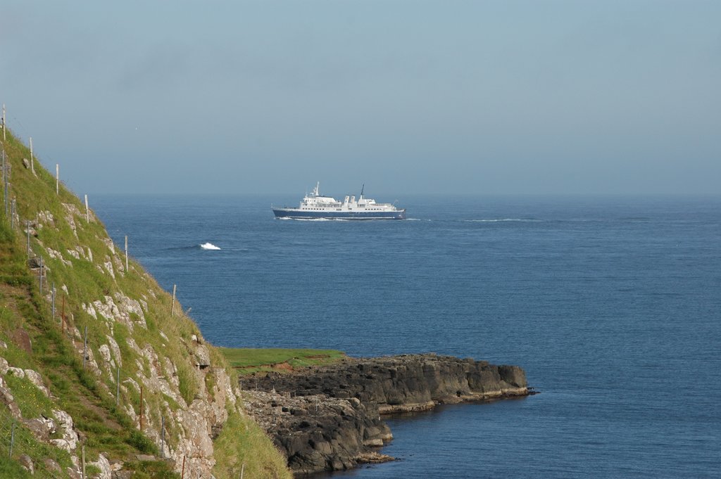 A ferry passing by steep cliffs on Suðuroy