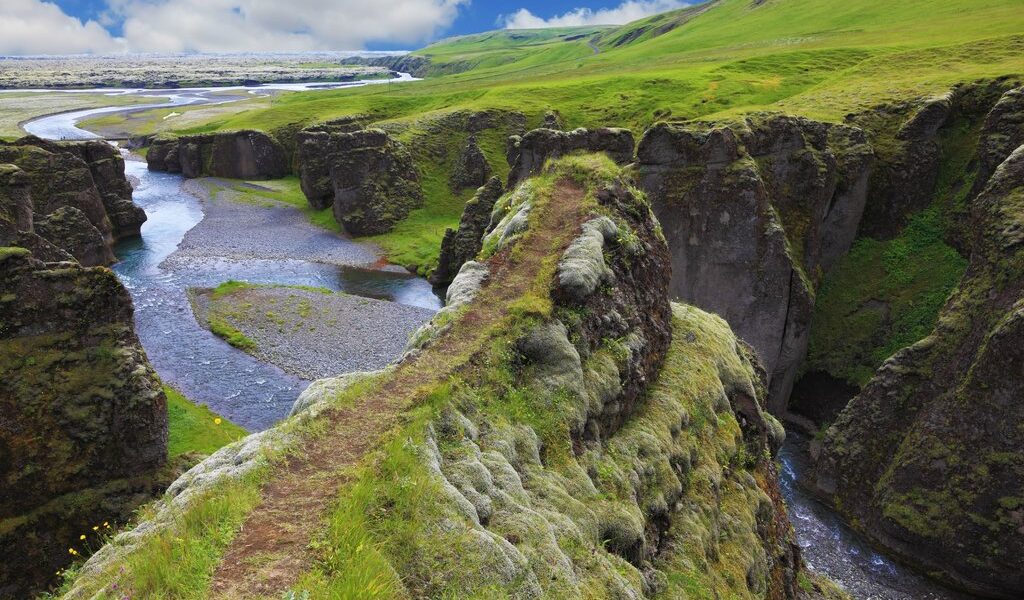 The picturesque canyon Fjadrargljufur;, rocks with yellowed grass and blue water of the river. Never