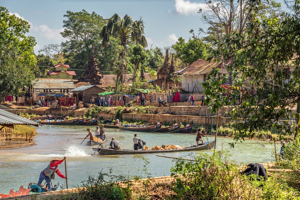 Tourists and locals travel by traditional long riverboats to the ancient city of Inwa