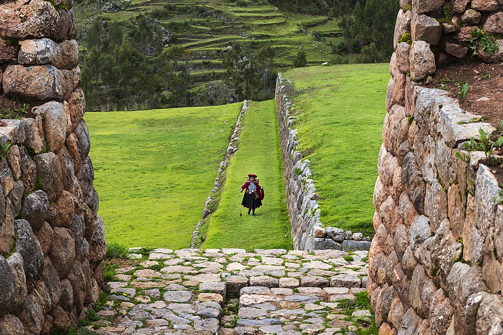 Peruvian woman walking through the Inca ruins of Chinchero