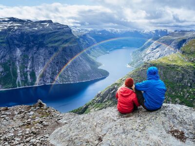 Couple sits on rock and looks at mountains near Trolltunga. Popu