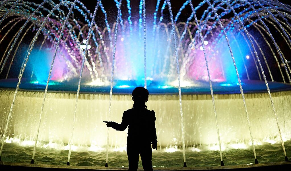 Small Kid Play With Colorful Fountain