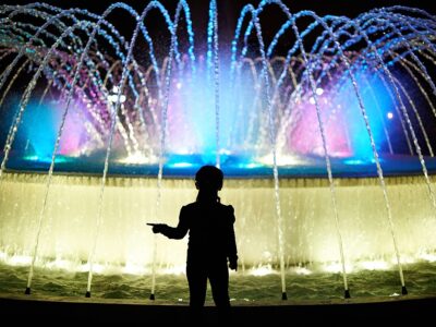 Small Kid Play With Colorful Fountain