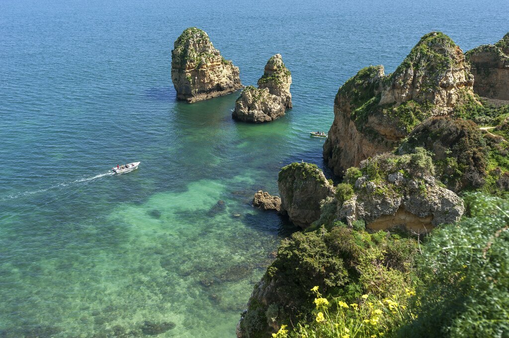 A boat travels around the rocky coast of Ponta da Piedade