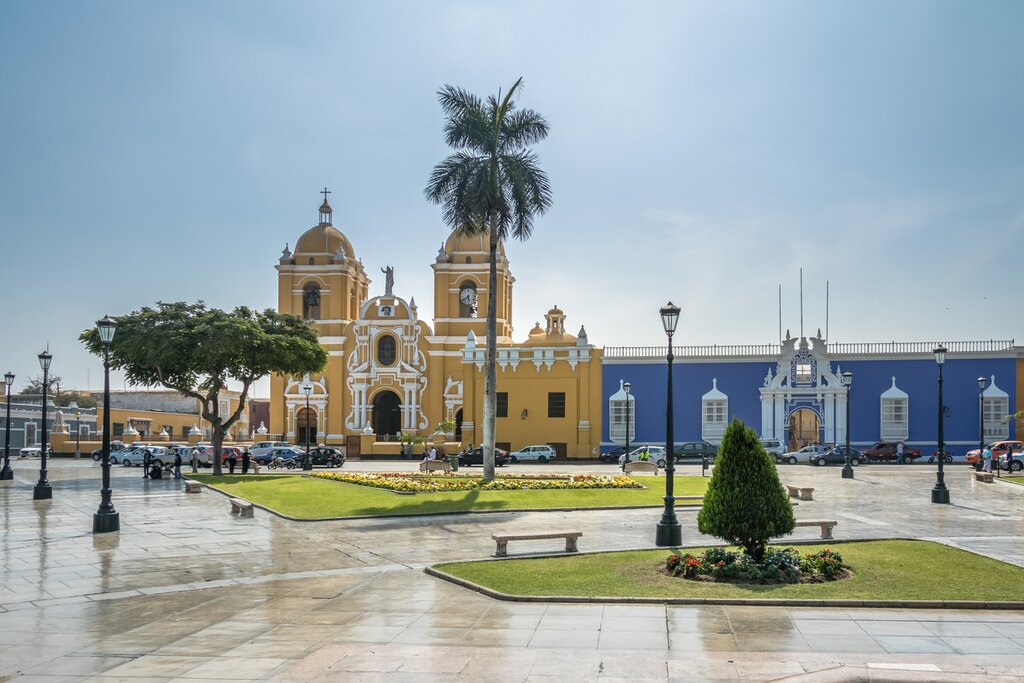 Street view of Trujillo's Plaza de Armas with the yellow cathedral and a blue public building