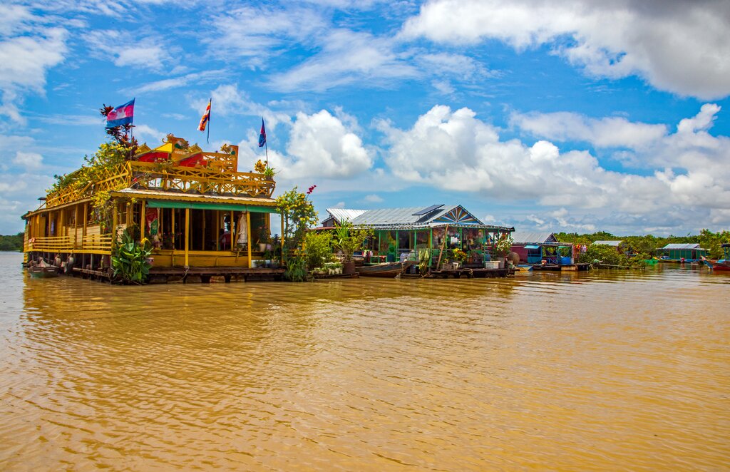 Photo of two floating buildings in Tonle Sap Lake; one temple with flags on the roof and one other building