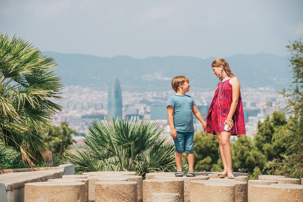 A brother and sister stand against a backdrop of Barcelona