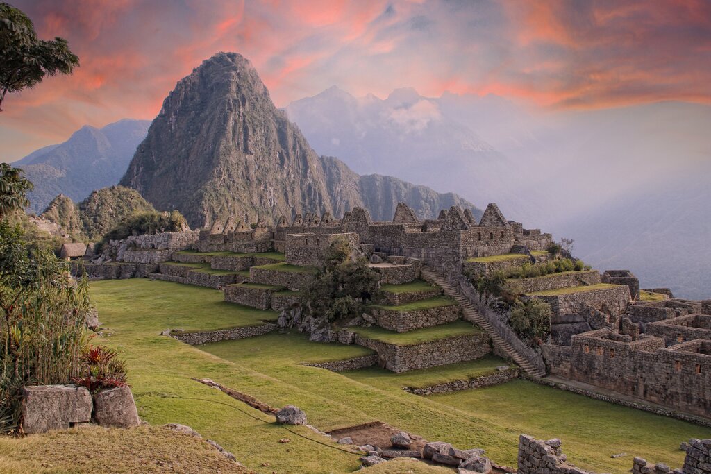 View of the  surroundings of the interior of Machu Picchu in a pink summer sunrise. A mountain is visible in the background