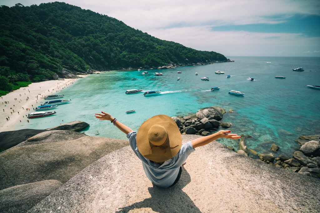A traveller sitting up high overlooking a sandy beach