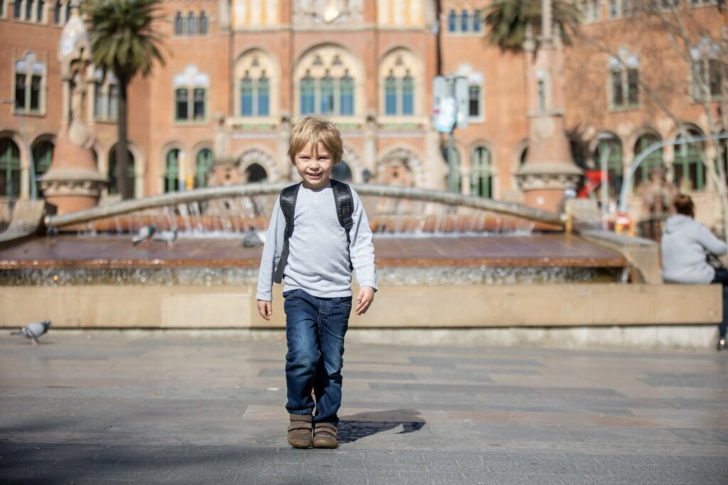 Child in grey sweatshirt walks in Barcelona