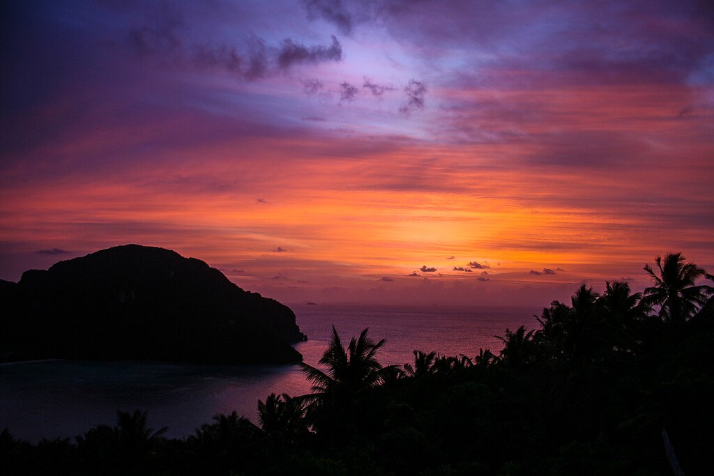 Aerial photo of a vibrant sunset with yellows, pinks, and purples over one of the Phi Phi Islands