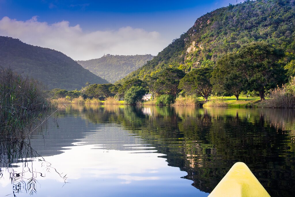 Scenic river canoe trip with tranquil reflections of mountains and trees on river edge near Kynsya