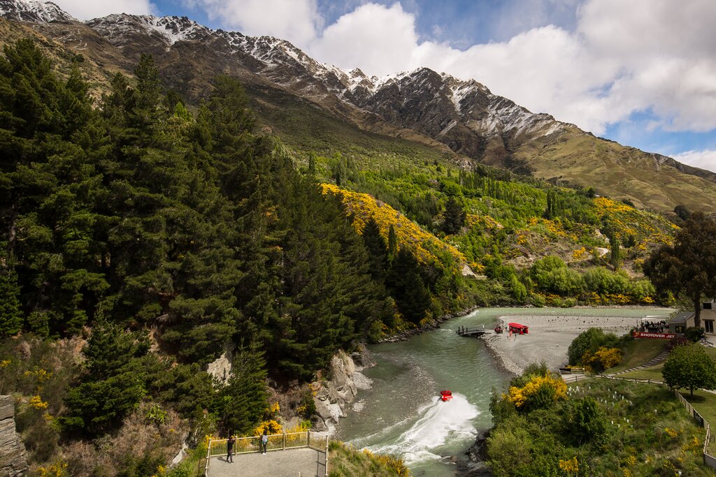 Aerial view of Shotover River, NZ, with red Shotover River Jet Boat speeding through the water
