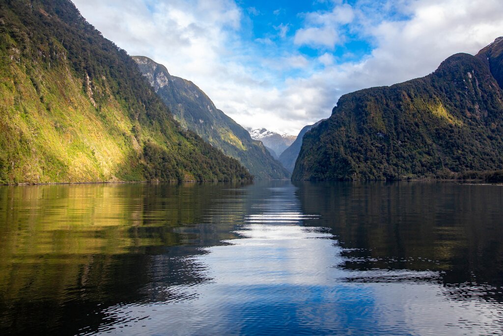photo of the calm water of Doubtful Sound with green valley walls on either side